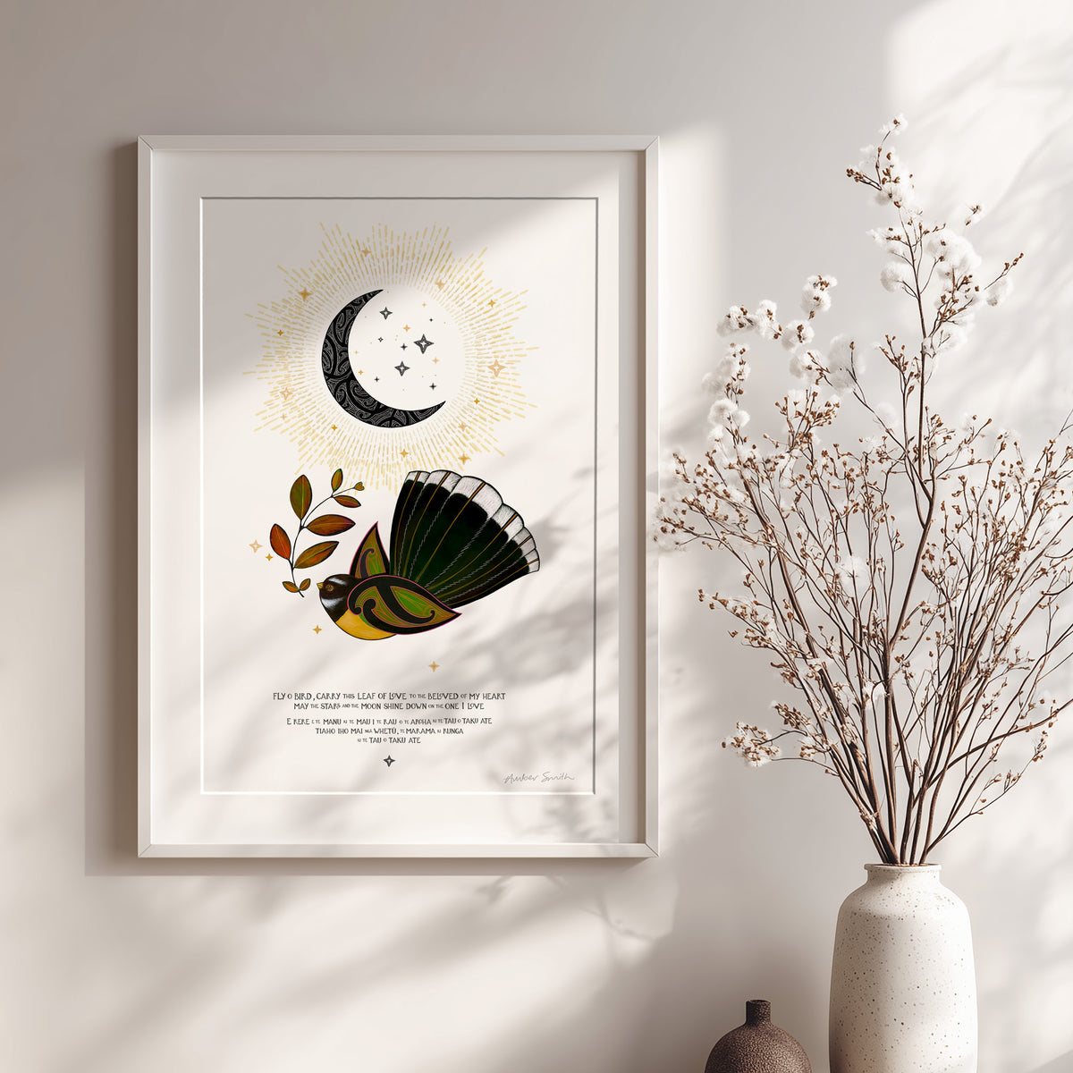 New Zealand pīwakawaka art print, E Rere E Te Manu – The Beloved of My Heart, featuring a fantail carrying a leaf of love beneath a crescent moon, with golden rays and stars and a blessing in te reo Māori and English. Shown with white frame.