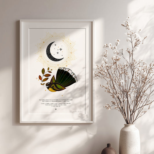 New Zealand pīwakawaka art print, E Rere E Te Manu – The Beloved of My Heart, featuring a fantail carrying a leaf of love beneath a crescent moon, with golden rays and stars and a blessing in te reo Māori and English. Shown with white frame.