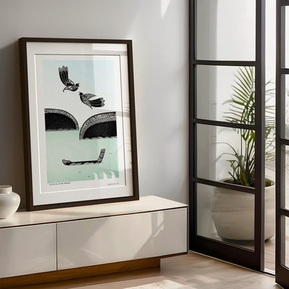New Zealand tūī art print, He Waka Eke Noa – We Are All in This Together, featuring tūī flying above a waka on the sea, with hills and flowing kōwhaiwhai patterns representing connection, unity and working together. Framed in large size in lounge room with natural light .