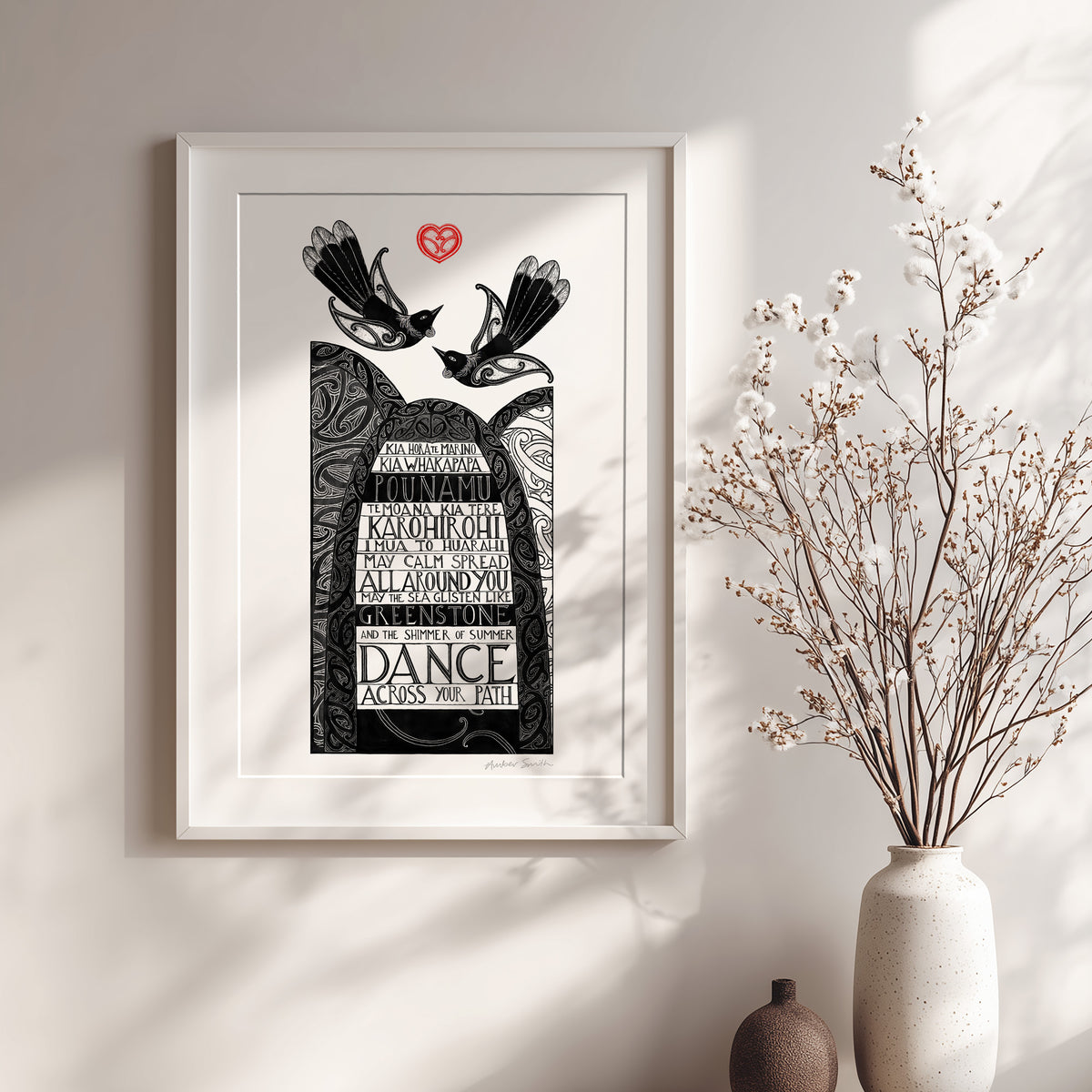 New Zealand art print, Kia Horo te Marino, featuring tūī birds, koru arches and kōwhaiwhai patterns, with a traditional karakia in te reo Māori and English wishing peace and beauty along life's journey. Shown with white frame and vase of dried flowers.