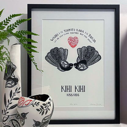 framed in studio kihi kihi kiss kiss nz wall art print by Amber Smith. With piwakawaka fantail and koru aroha love heart. Te reo maori and english inscription, let us keep close together not far apart.
