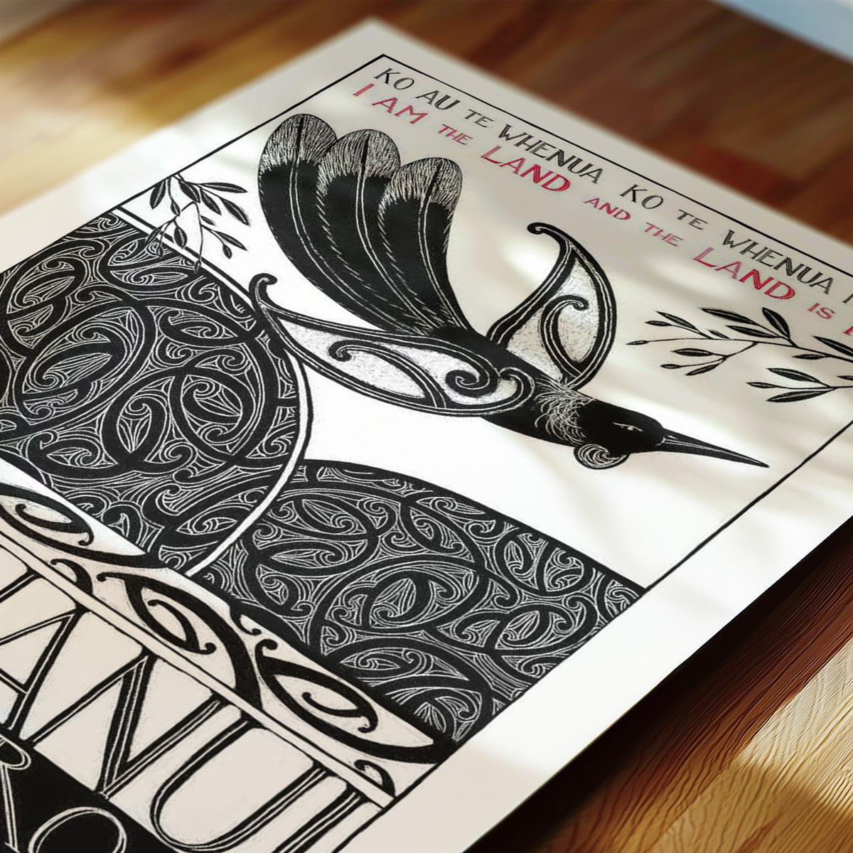 Detail of New Zealand tūī art print, Ko au te Whenua – I Am the Land, featuring a tūī flying over the land and sea, with the te reo Māori whakataukī “Ko au te whenua, ko te whenua ko au” and its English translation, “I am the land and the land is me”.