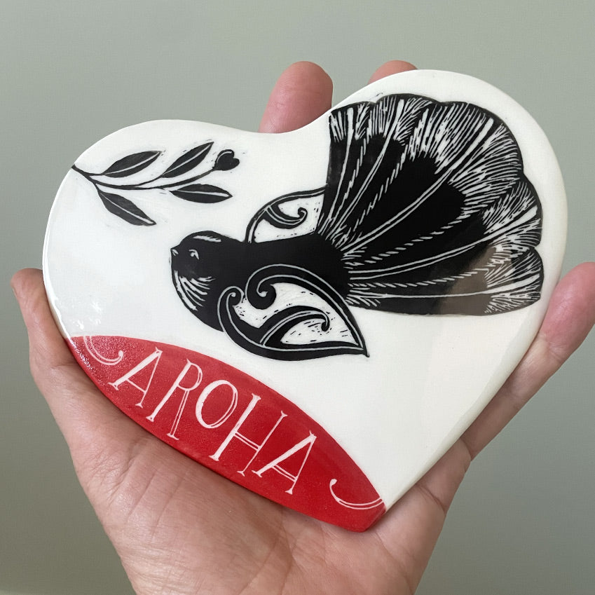 Ceramic wall heart with piwakawaka fantail and the word aroha